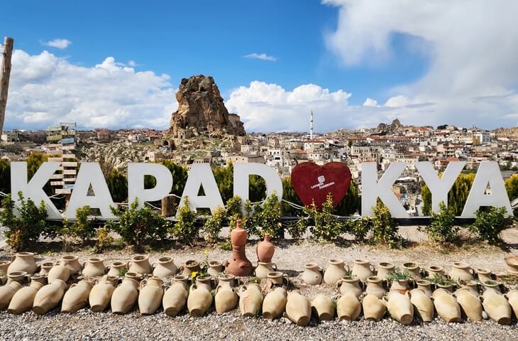“Kapadokya” yazısı önünde Ortahisar Kalesi ve taş evlerden oluşan panoramik Kapadokya manzarası